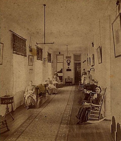 A long asylum corridor with patients seated along its length